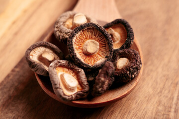 Edible dehydrated shiitake mushrooms in a rustic wooden spoon close up