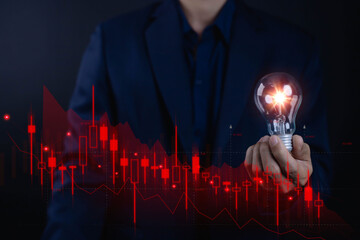 holding glowing light bulb with red stock market graph showing decline. Concept of innovation during financial crisis, creative business idea, and risk management insight.