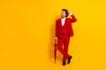 Playful red suit man with hat strikes stylish pose against bright yellow background for bold fashion ad campaign