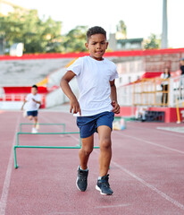 Fototapeta premium Young children having athletic exercise class running on the track, healthy lifestyle and children sport education concepts