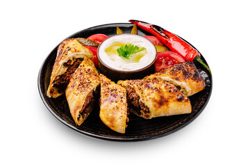 Savory meat rolls with fresh vegetables and yogurt dip on a black plate
