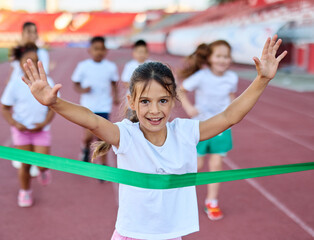 Young children having athletic exercise class running on the track, healthy lifestyle and children sport education concepts, finish line winner celebration, victory and success