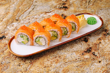Fresh salmon sushi rolls served on a white plate with wasabi and ginger