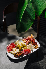 Assorted cheese and charcuterie platter with greens in a cozy setting