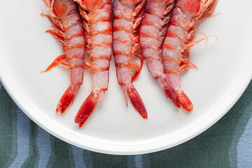 Top view of fresh raw shrimp on plates with blue abstract background