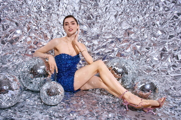 Festive celebration with a young woman wearing sparkling attire among shiny disco balls