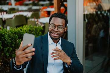 African man having video call on smartphone at cafe