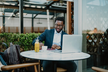 Black businessman remote working on laptop at cafe