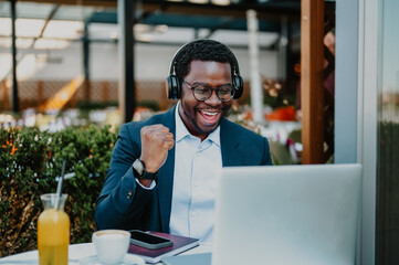 African man celebrating success using laptop outdoors