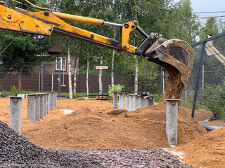 Soil spills out of an excavator bucket, work at a construction site