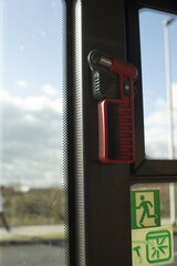 Emergency hammer and exit indicator clearly seen against textured glass with reflections and safety stickers