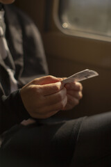 Traveler scrutinizes train ticket in cozy setting, Closeup of fingers inspecting printed train pass details