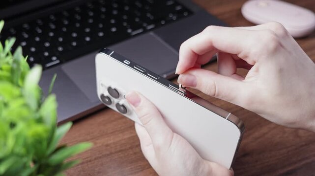 Hands opening SIM card slot on a modern white smartphone using an ejector tool, signifying mobile device activation, network connectivity, and digital lifestyle