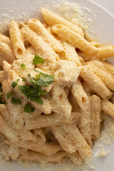 Creamy pasta delight, Rich cheese sauce with herbs, Hearty penne dish adorned with fresh herbs, Indulgent pasta covered in savory sauce with grated cheese