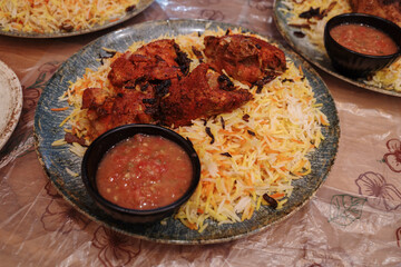 A large plate of Middle Eastern chicken Mandi or Biryani rice with red sauce.
