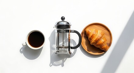Top-down view of a simple breakfast with black coffee, a French press, and a croissant on a white table.