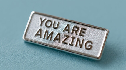 Metal plaque with 'You Are Amazing' message on blue background.