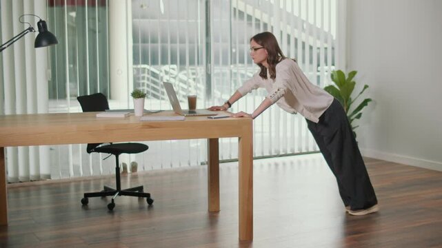 Employee Engagement. Female Worker Practices Desk Push Ups in Office, Promoting Healthy Workplace, Stress Relief, Wellness Routine, Positive Culture, Productivity Hacks, and Future of Work Balance