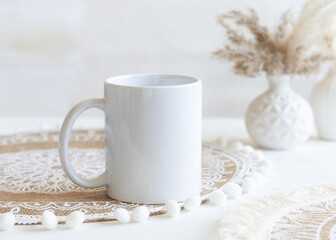 White blank coffee mug on boho placemat near pampas grass Close up, mockup for print on demand