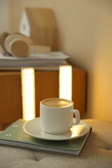 Coffee, notebook on pouf and portable LED lamps at home, closeup