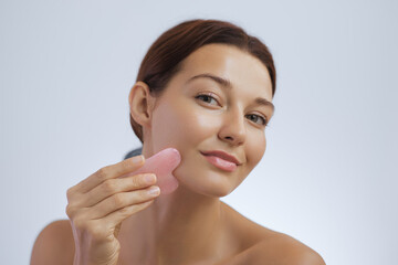 Young Woman Massaging Cheek with Gua Sha Stone in Beauty Close-Up