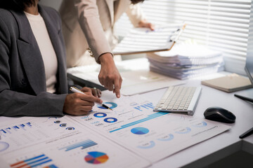 Businesswomen analyzing financial data, collaborating on reports, planning strategy