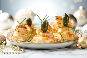 Tasty snacks with puff pastry, olives, red caviar and Christmas decor on white marble table against grey background, closeup