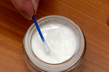 Applying a cream with a cotton swab in a cozy setting
