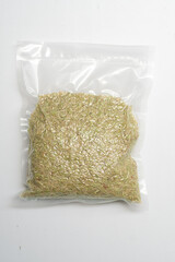 A vacuum-sealed clear plastic bag filled with Milk Stage Rice or light brown rice grains on a white background.