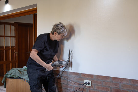 Mujer adulta perforando pared con taladro
