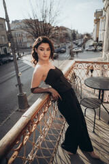 Woman in black leaning against balcony railing with city view