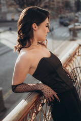 Side view of elegant woman in black leaning on railing