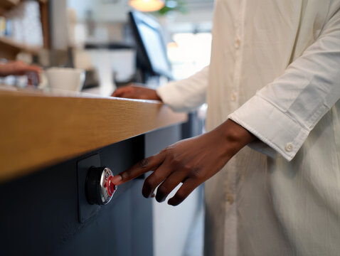Finger pressing a red emergency panic button on a store counter.