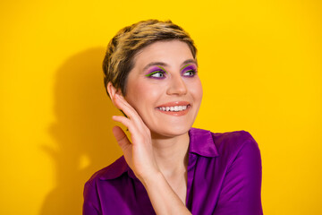 Fototapeta premium Young glamorous woman with short blonde hair in a purple blouse smiles against a bright yellow background