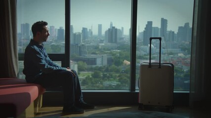 A contemplative traveler finds peace and reflection in a stylish urban hotel room setting