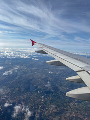 Airplane Wing Above Clouds and Scenic Landscape from Window View, Travel and Aviation Concept
