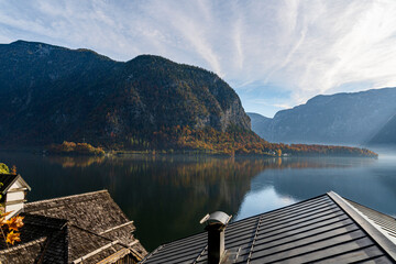 Autumn Mountain Lake Landscape with Colorful Forest Reflection and Traditional Rooftops under Clear Blue Sky