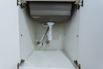 under sink plumbing, sink cabinet with exposed pipes, accessible undersink plumbing for repairs and installation, open undersink cabinet displaying plumbing and supply valves