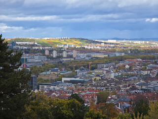 Germany, Stuttgart downtown city centre aerial panorama view above the skyline houses roofs buildings and cranes in autumn season, colorful vineyards