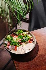 Fresh salad bowl with colorful ingredients in a cozy cafe setting