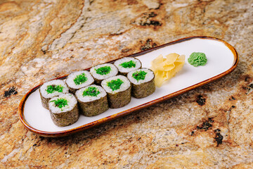 Delicious sushi rolls presented on a white dish with condiments