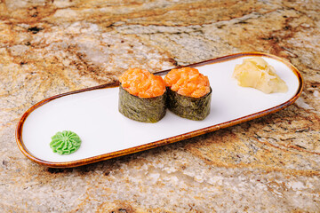 Fresh sushi served on a white plate with wasabi and pickled ginger