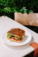 Delicious sandwich on a plate in a modern cafe setting with greenery