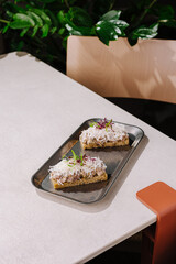 Two delicious open-faced sandwiches served on a tray in a cozy cafe setting