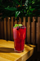 Refreshing crimson drink with mint and berries on wooden table