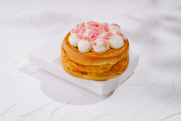 Delicious cake topped with pink frosting on a white surface
