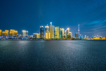 Empty asphalt square with financial district skyline and modern buildings at night.
