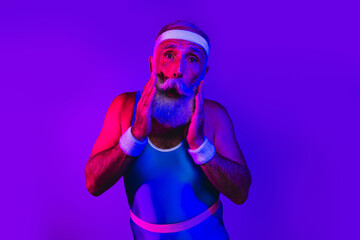 Bearded senior athlete in retro sportswear under purple blue neon lights posing in a playful wellness moment
