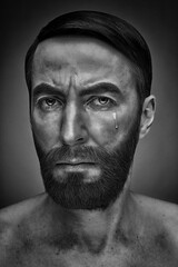 Dramatic black and white portrait of a sad man crying a single tear. Close-up on an emotional face expressing grief and pain. Mental health concept.