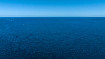 Obraz premium Aerial view of the blue sea stretching to the horizon. There are no boats and the sea surface is calm and clean.